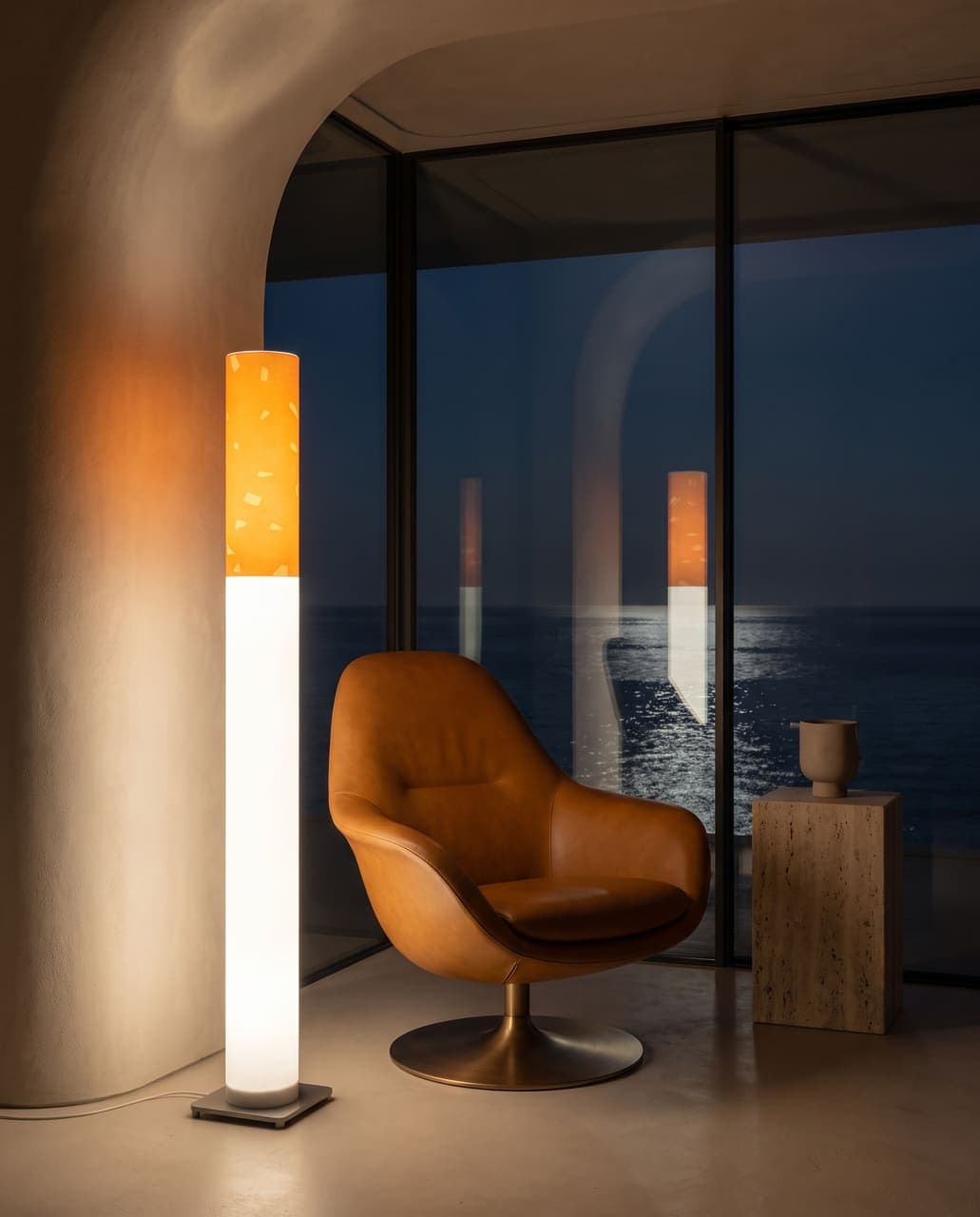 The lit floor lamp beside a caramel leather swivel chair at a window over a dark sea with a moon path on the water